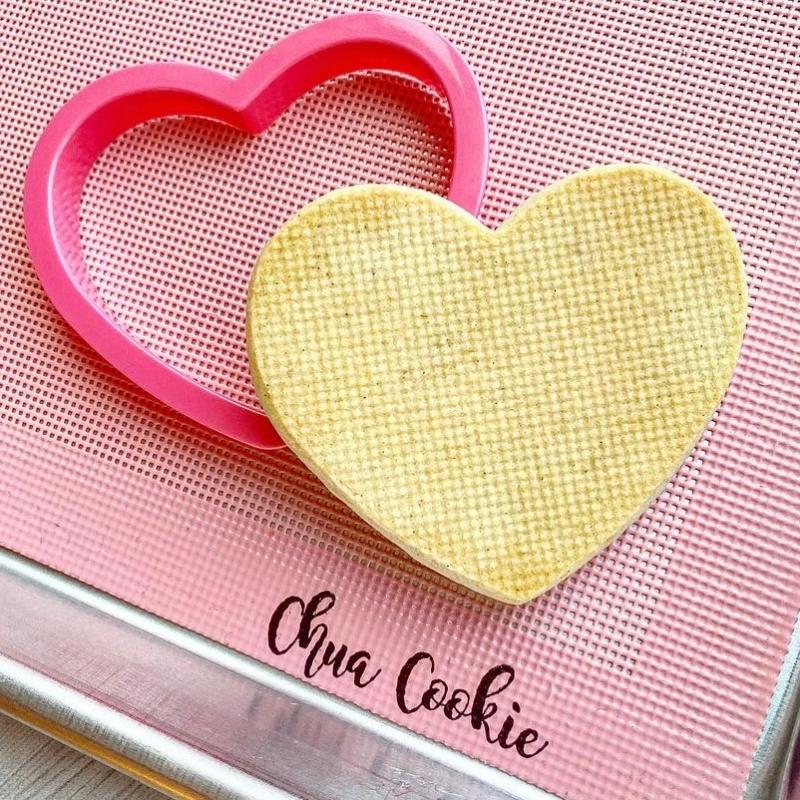 pink perforated cookie mat with pink cookie cutter and cookie baked