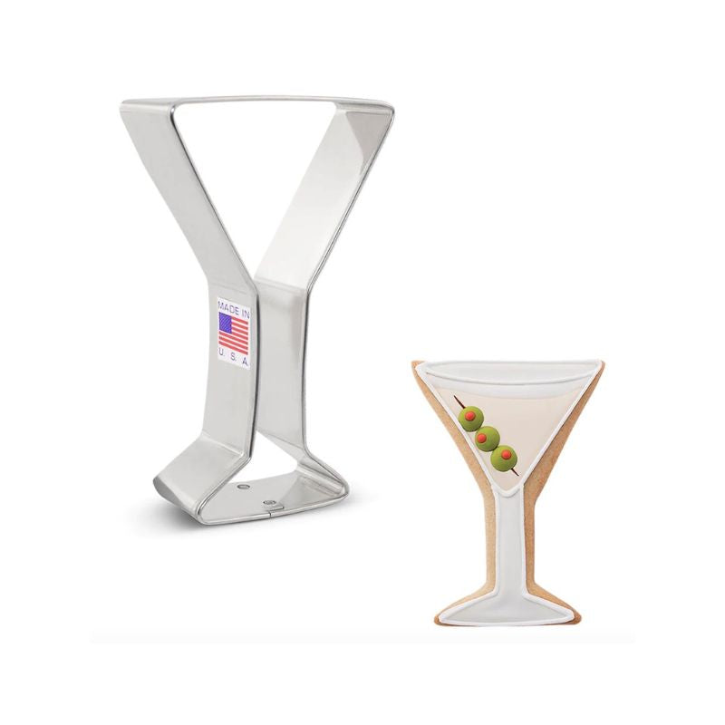 Metal cookie cutter in the shape of a Martini Glass and cookie beside decorated as a martini with olives and vodka in