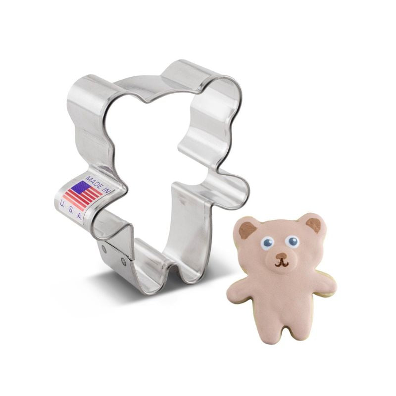 Metal mini bear cookie cutter with made in the usa with flag sticker on side beside light brown royal icing and blue eyes