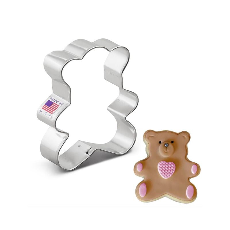 Metal cookie cutter with made in USA American flag sticker on side next to a royal icing decorated cookie with brown colour and pink paws and hearts