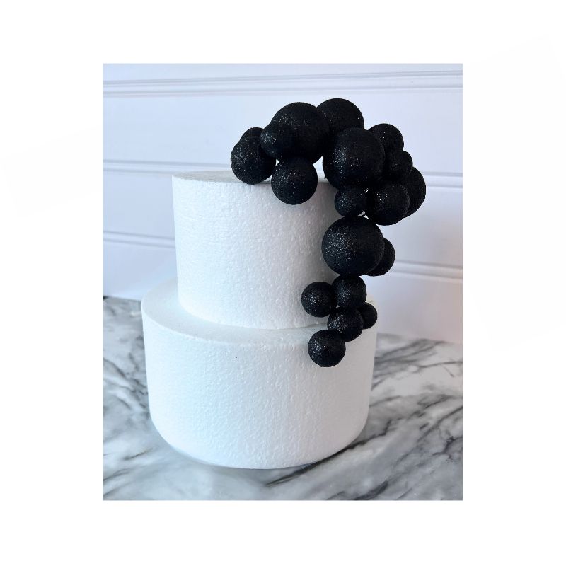 2 level white cake with multi sized black glitter cake balls 