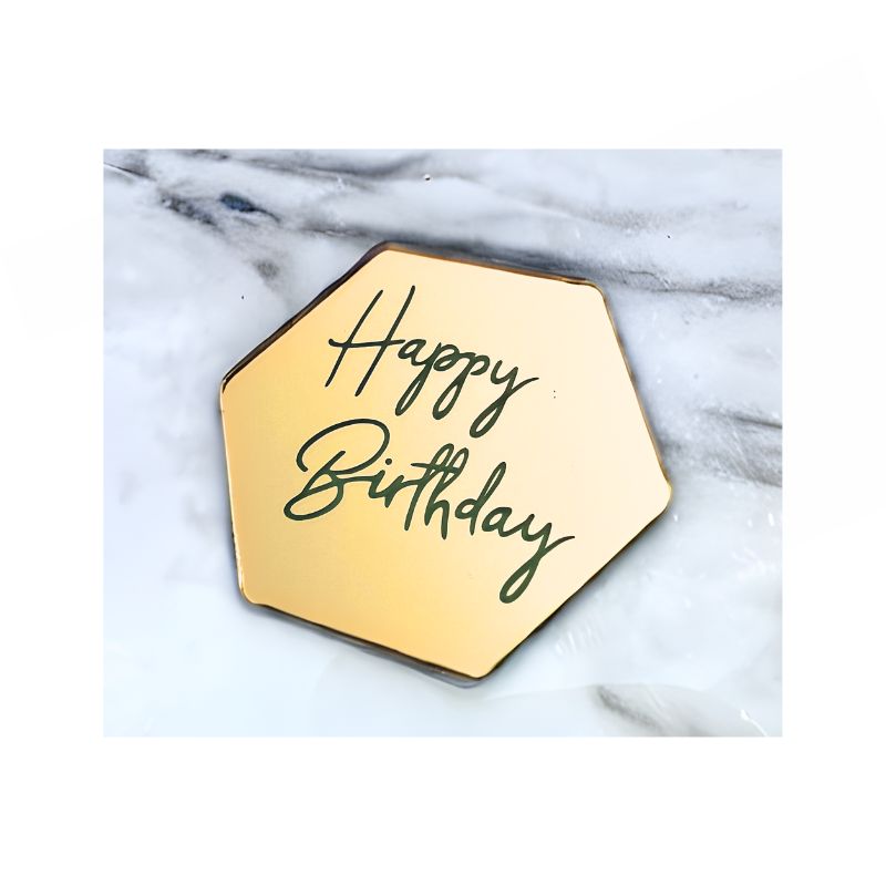 gold hexagon with happy birthday in script writing on marble background