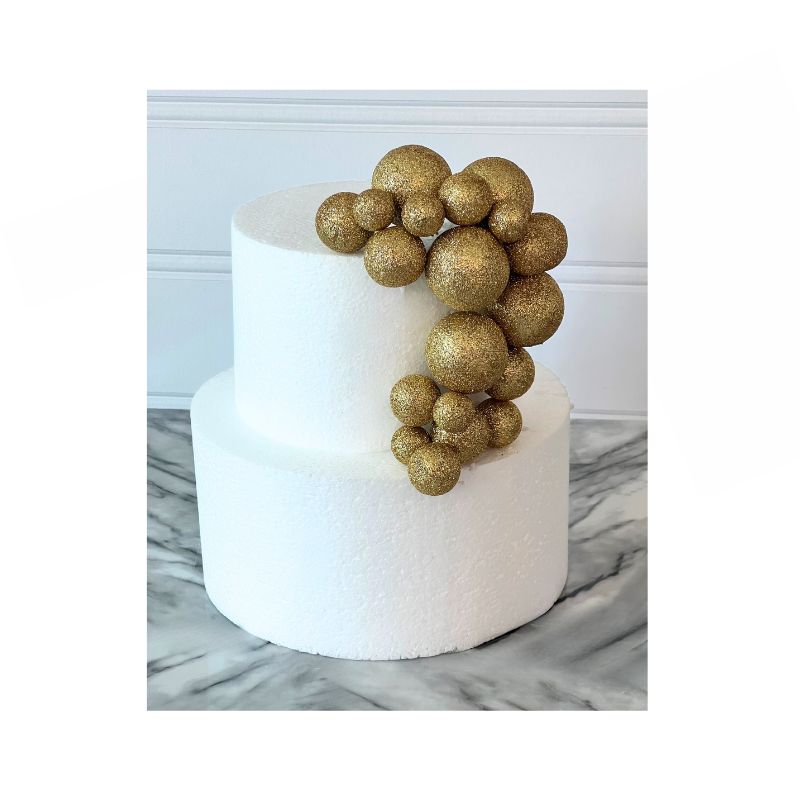 white cake with different sized Glitter cake balls