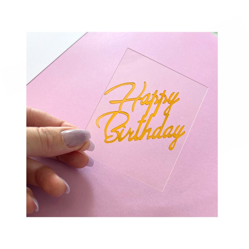 Happy birthday written in gold on clear rectangle plaque