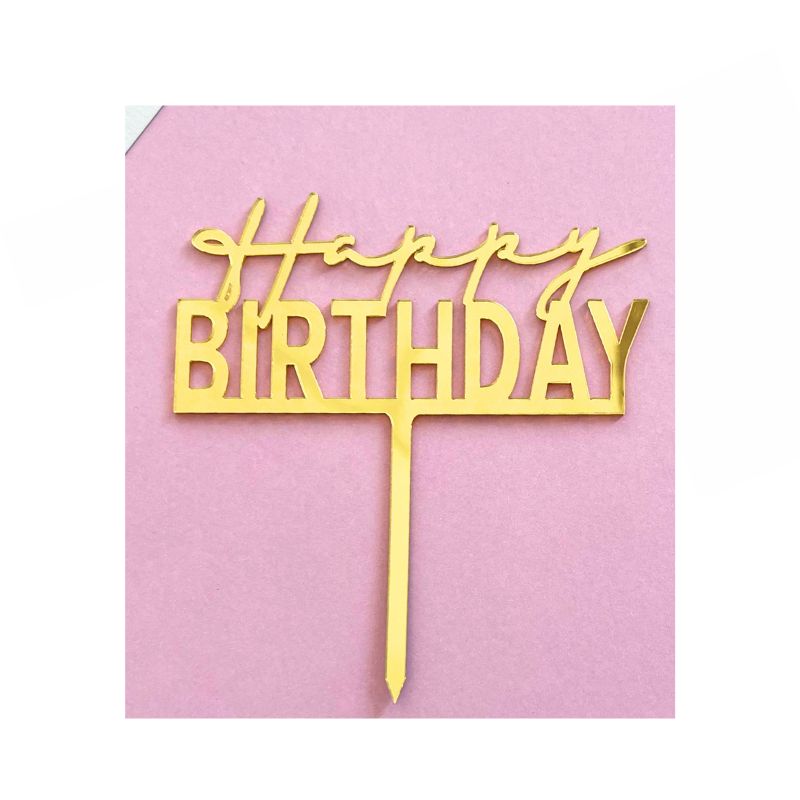 gold happy birthday cake topper on pink background