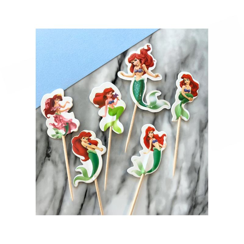 6 different little mermaid characters on sticks for cupcakes on marble background