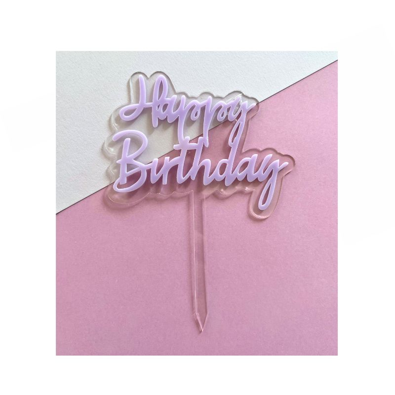 Pastel purple happy birthday script on clear cake stick on pink and white background