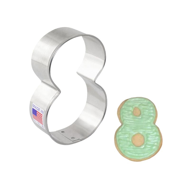 Stainless steel cookie cutter in the shape of a number 8 and cookie beside with green buttercream icing