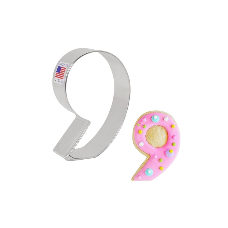 Metal cookie cutter with made in the USA and American flag sticker on side and number nine cookie decorated with pink background and blue yellow and green dots