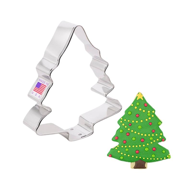 Stainless steel cookie cutter in the shape of a Christmas tree and a holiday Christmas tree decorated with green background and gold yellow and green decorations 