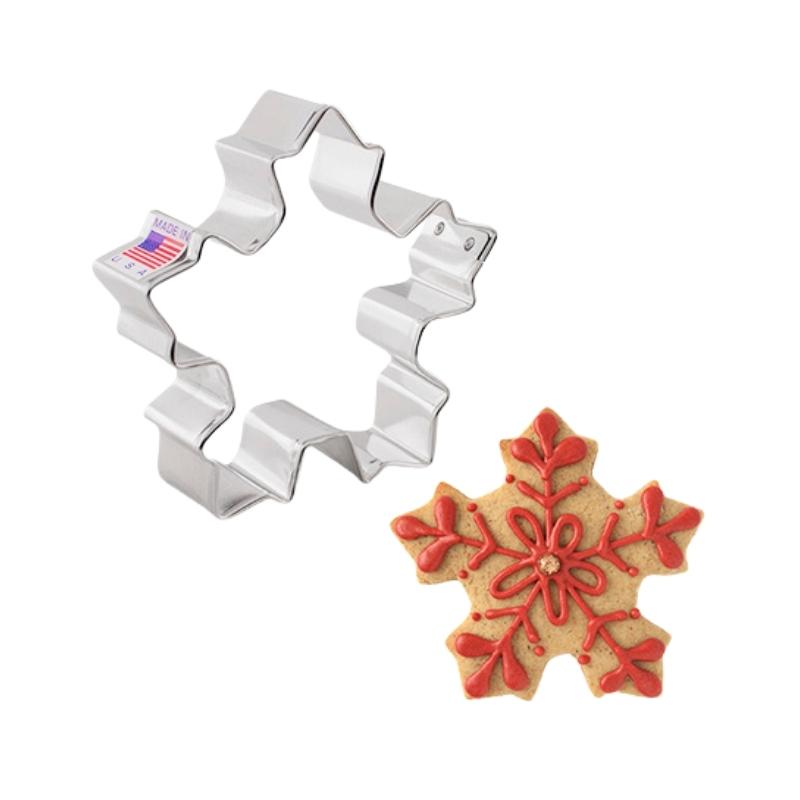 Christmas and holiday festive snow flake cookie cutter that is metal and cookie that is decorated with royal icing in red