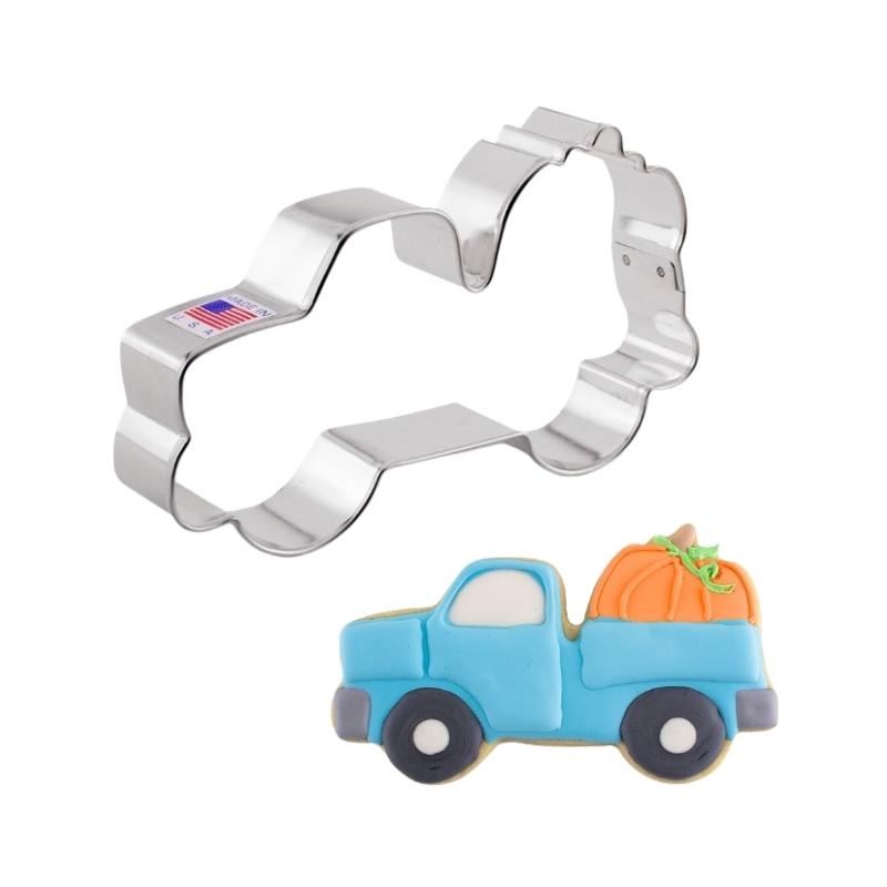 Metal cookie cutter of a truck with pumpkins and decorated using cookie tools and royal icing