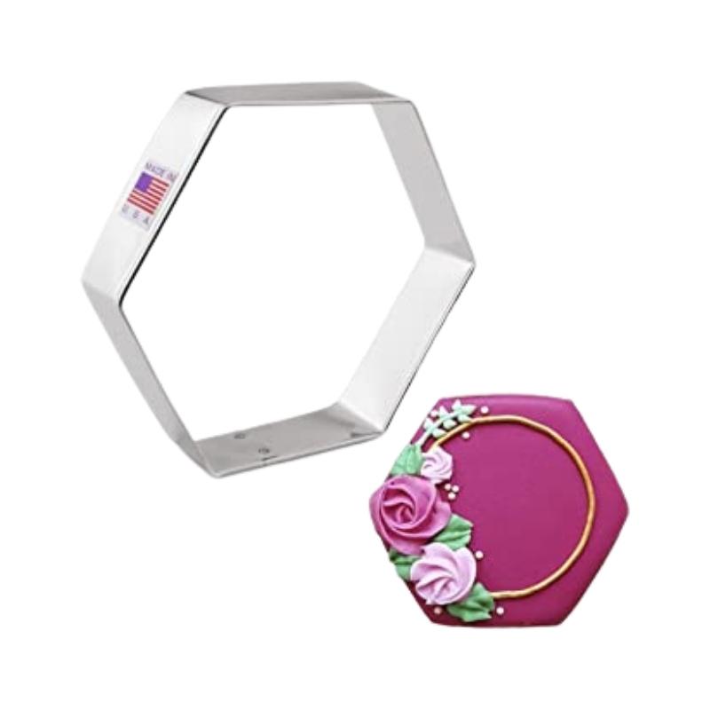 Stainless steel cookie cutter in the shape of a hexagon  and wedding cookie decorated with burgundy with flowers and gold circle