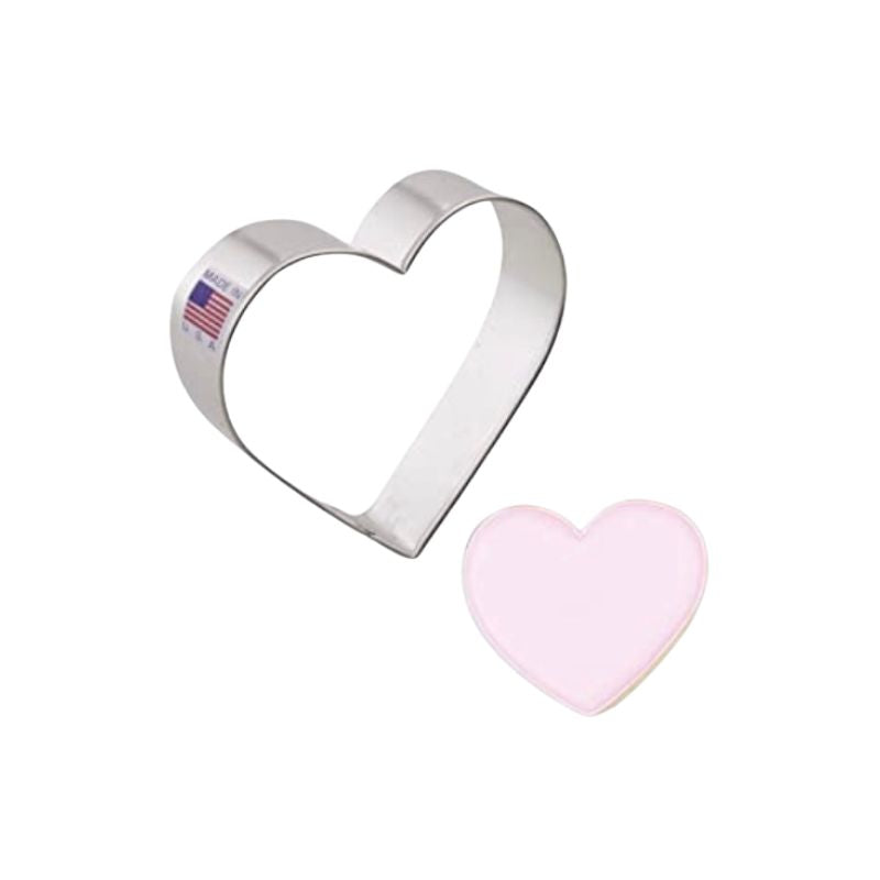 Metal cookie cutter in the shape of a mini heart and bedside is a heart with pink icing