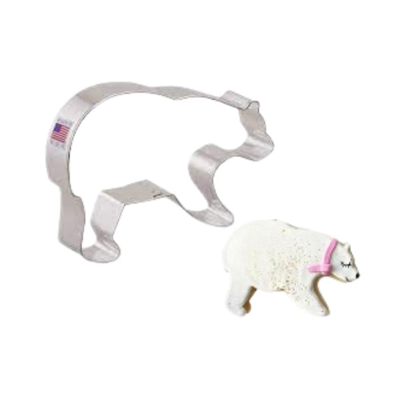 Metal cookie cutter made in the USA with flag and cookie in the shape of a polar bear decorated with white royal icing and pink scarf