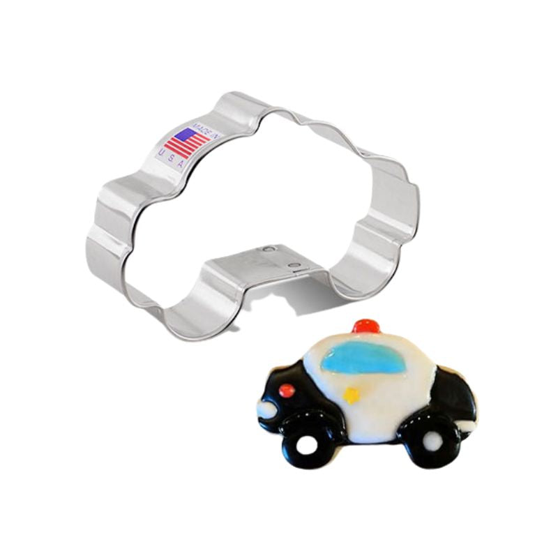 Metal cookie cutter with made in USA stickers and beside is police car with royal icing details in black white and blue