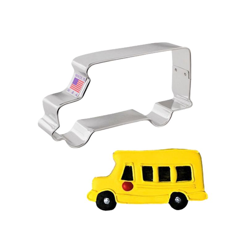 Metal cookie cutter in the shape of a school bus made in the USA and beside a yellow royal icing decorated cookie with black windows and wheels