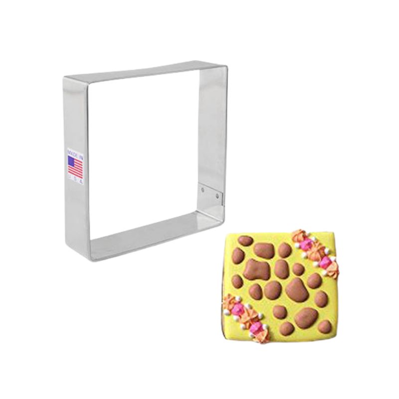 Metal cookie cutter in the shape of a 3.5inch square next to a decorated cookie with yellow background and brown pebbles