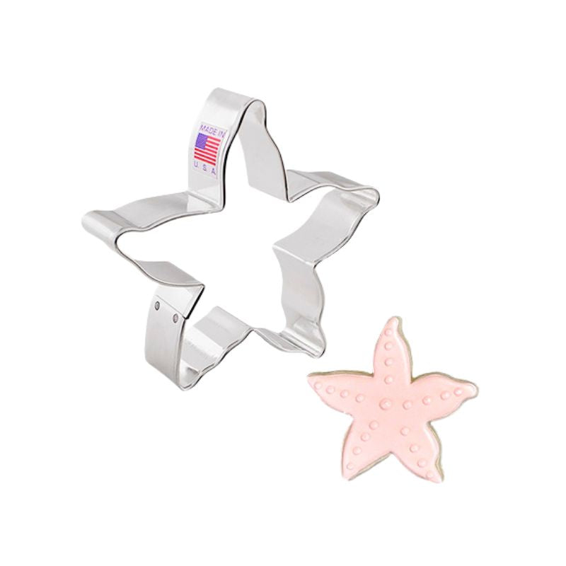 metal starfish cookie cutter next to a decorated cookie in light pink with pink details