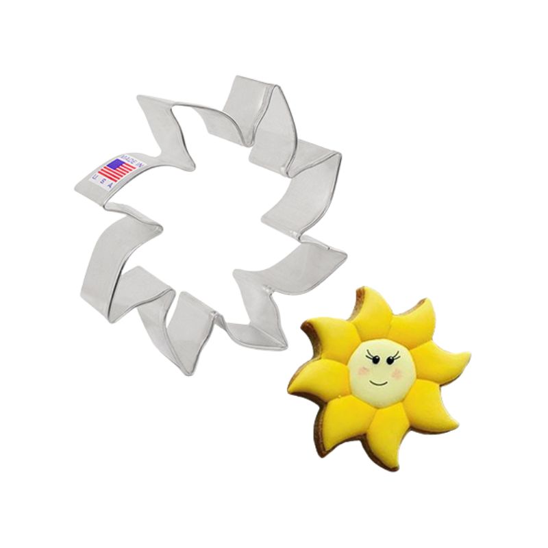 Metal cookie cutter with American flag sticker next to a decorated sun with yellow rays and lashes on smiley face