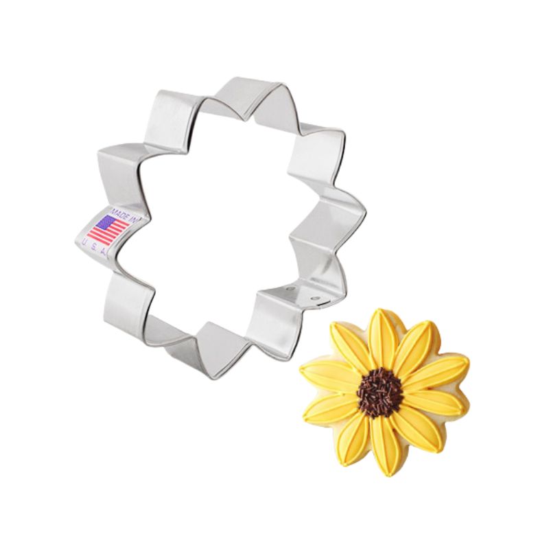 Sunflower cookie cutter metal and made in the USA beside a royal icing decorated sugar cookie with yellow petals and brown centre 