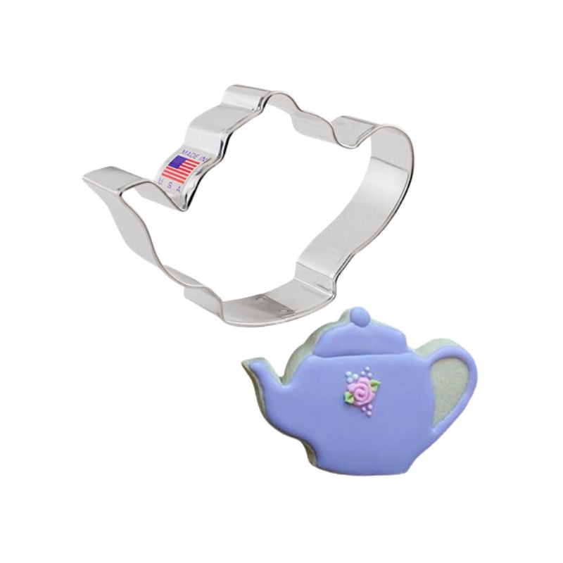 Metal Teapot cookie cutter made in the USA with American flag sticker next to a decorated sugar cookie teapot pot in purple with pink flowers