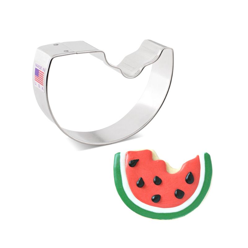 Metal watermelon shaped cookie cutter next to a sugar cookie shaped like a watermelon with bite taken out iced with royal icing in red white and green with black seeds