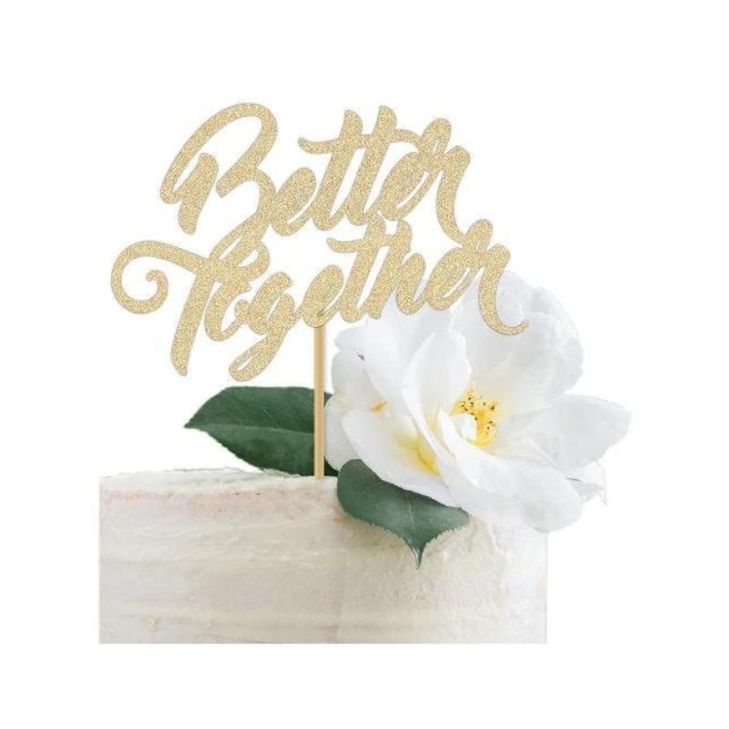 Gold glittering cake topper saying Better Together on cake with white flower and green leaves